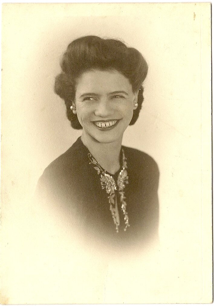 Aunt Mabel — a sepia studio portrait of a smiling woman with dark waved hair and a sparkling brooch.