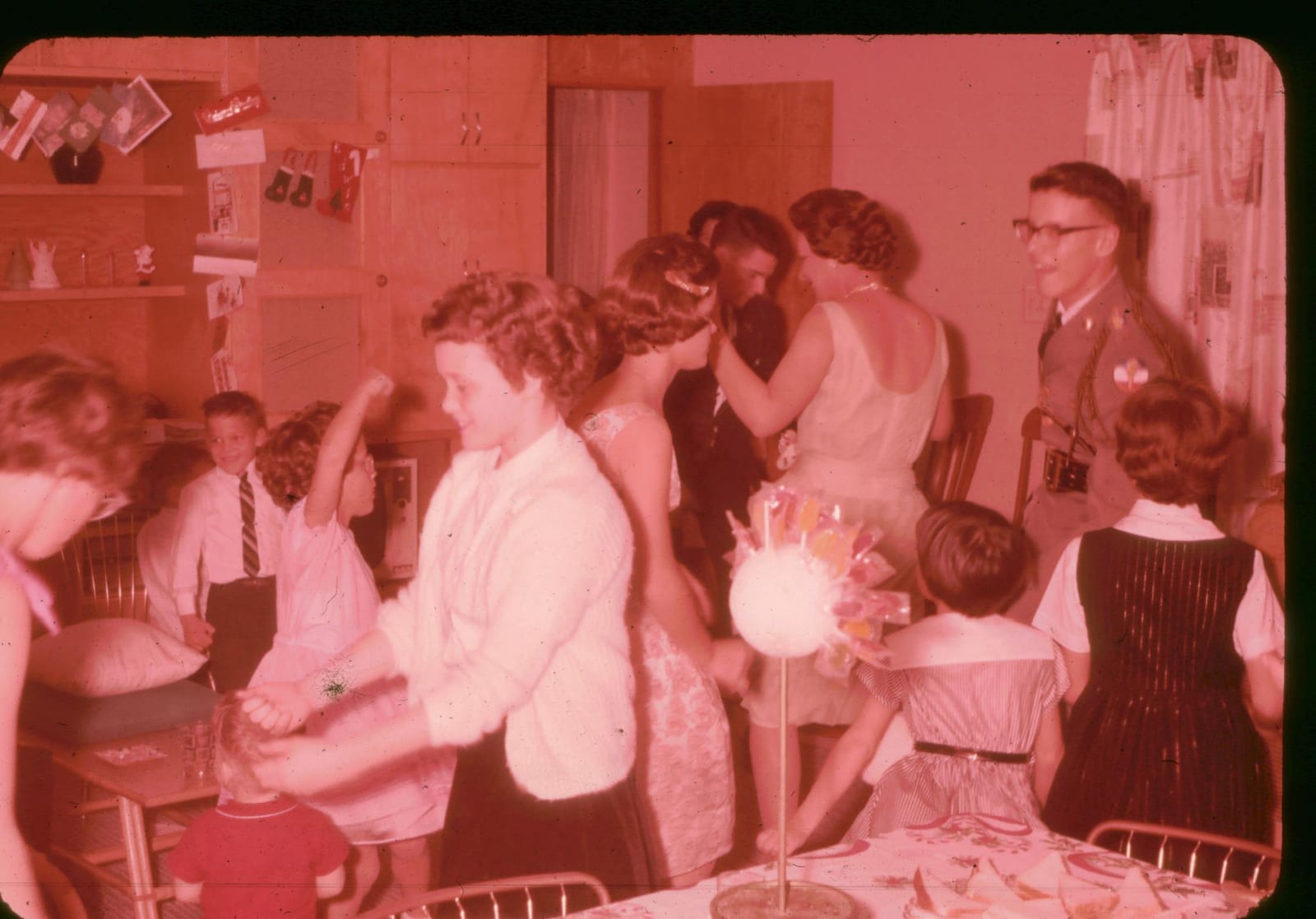 Cousins dancing at a Christmas party, Christmas cards and stockings pinned along the shelves behind them.