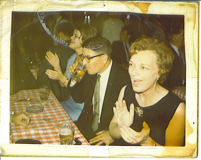 Rob's mother Kathy, his Uncle Bob and his grandmother Mary Jean around a table together, mid-laugh, clapping.